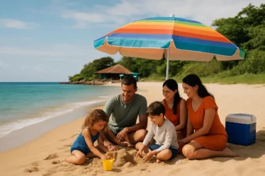 Familia na areia da Praia do Curral com mar calmo e quiosque ao fundo